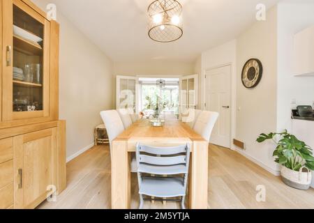 a dining room with wood flooring and white walls, there is a light fixture in the center of the room Stock Photo