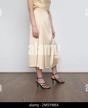 Female model wearing beige camisole silk top and wrapped midi skirt. Stylish and elegant monochrome summer outfit. Fashion Studio shot. Stock Photo