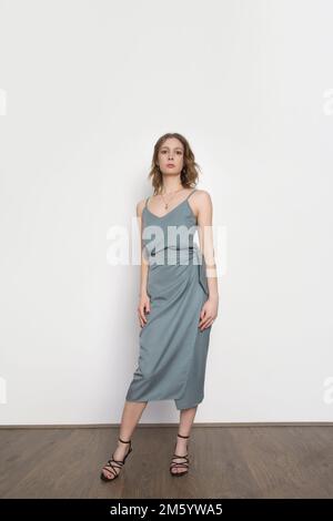 Female model wearing bluish grey camisole silk top and wrapped midi skirt. Stylish monochrome summer outfit. Fashion Studio shot. Stock Photo