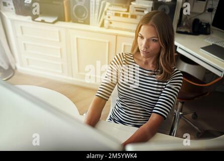 Shes dedicated to her business. High angle shot of a young woman working on a computer in her home office. Stock Photo