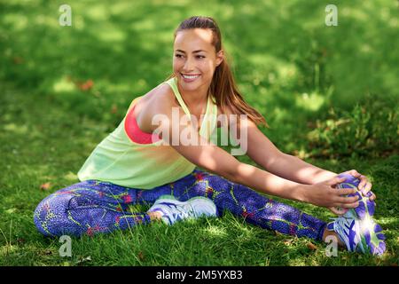 Flex arms. Stretch legs. Turn heads. a young woman stretching her legs before a workout. Stock Photo