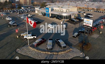 An aerial photo out front of a Cheverolet dealership, new cars are seen filling the parking lot and the Canadian flag waving in the morning. Stock Photo