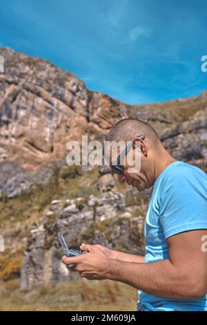 Young man with modern drone in mountains, back view Stock Photo
