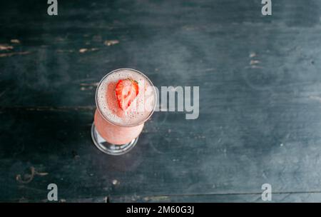 Top view of strawberry smoothie on dark wooden table. View of strawberry milkshake on dark wood. View from above of delicious strawberry smoothie Stock Photo