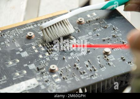 mechanic's point of view Use a spray and brush to clean the graphics card. Stock Photo