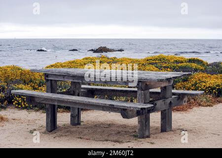 Wooden table and bench near the ocean on 7 Mile Drive. 17 Mile Drive is a scenic road through Pebble Beach and Pacific Grove on the Monterey Stock Photo