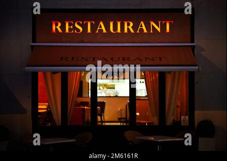 23 dec 2022 - London UK: illuminated restaurant sign at night over restaurant with outside table and seating Stock Photo