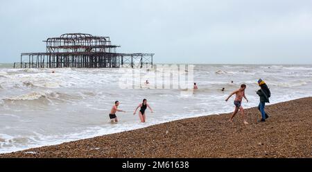 Brighton UK 1st January 2023 - New Years Day swimmers take a dip in the sea at Brighton near the West Pier in dull overcast weather : Credit Simon Dack / Alamy Live News Stock Photo