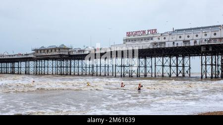 Brighton UK 1st January 2023 - New Years Day swimmers take a dip in the sea at Brighton in dull overcast weather : Credit Simon Dack / Alamy Live News Stock Photo