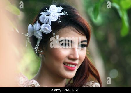 portrait of a smiling Indonesian woman. she wears white flower ornaments in her hair Stock Photo