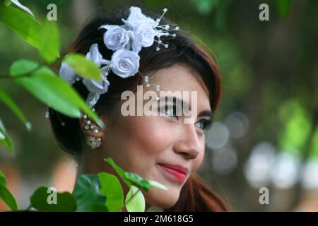portrait of a smiling Indonesian woman. she wears white flower ornaments in her hair Stock Photo