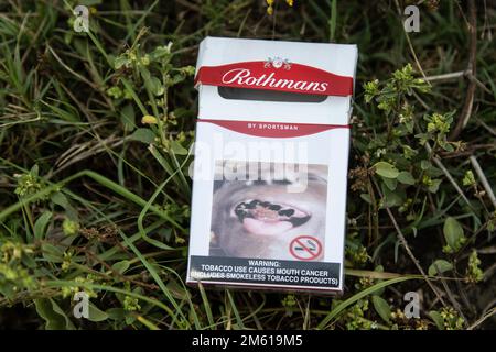 An empty packet of Rothmans Cigarettes with a health warning written 'Tobacco Use causes mouth cancer'  litters the environment near a popular entertainment spot in Nakuru. A study conducted by researchers at California’s UC Davis Comprehensive Cancer Center says nearly half of the deaths from 12 cancers are due to tobacco use. Stock Photo
