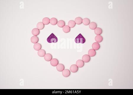 Sweets candies as heart with two glittering lilac hearts on white background. Valentines day concept. Flat lay. Stock Photo
