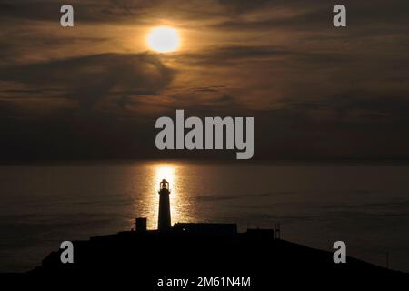South Stack Lighthouse silhouetted at sunset against the Irish Sea, South Stack, Anglesey, North Wales, UK Stock Photo