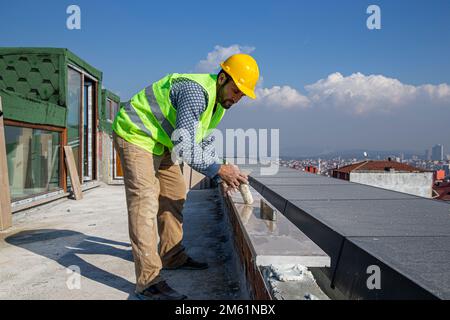 The builder is hitting the marble with a hammer and leveling it with a spirit level. The master replaces a polished marble handrail. Stock Photo
