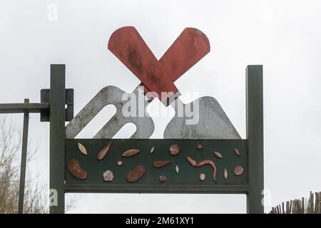Unusual metal sign at entrance to allotments with a trowel and fork, community gardening facility in Surrey, England, UK Stock Photo