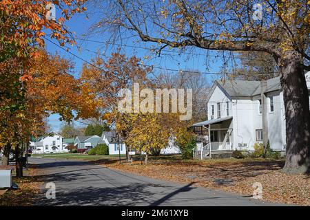 Small town residential street with white clapboard houses and trees ...