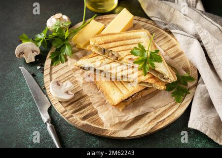 Delicious sandwich with grilled cheese, bacon and mushroom. Homemade breakfast on a dark stone tabletop. Stock Photo