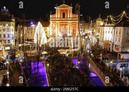 Crowds gather in the brightly lit Presernov Trg Square, by the three bridges, Ljubljana, Slovenia for 2022 / 2023 New Year's Eve celebrations Stock Photo