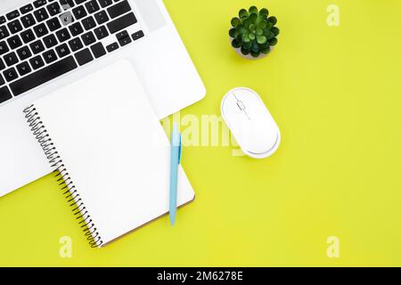 Laptop, computer mouse and blank notepad on green background, flat lay. Stock Photo