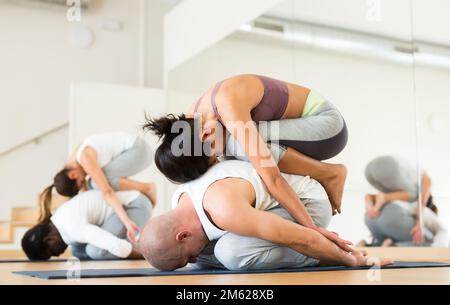 Couples practicing yoga with partner at studio Stock Photo