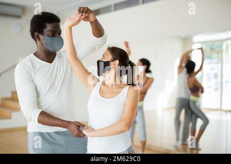 Group of multinational people in protective masks practicing dance techniques Stock Photo