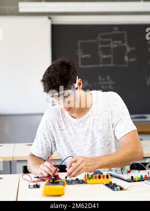 Young male student experimenting with electronic devices in the laboratory Stock Photo