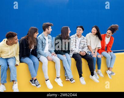 Group of multi-ethnic friends laugh and have a good time while talking to each other in a city. Diverse best friends Stock Photo