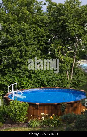 Above ground cedar wood swimming pool in residential backyard in summer. Stock Photo