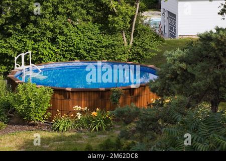 Above ground cedar wood swimming pool in residential backyard in summer. Stock Photo