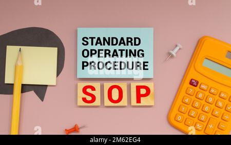 On a bright blue background, light wooden blocks and cubes with the text SOP Standard Operating Procedure. Stock Photo