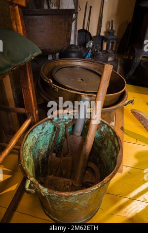 Hand tools in large antique patinated copper metal bucket in dining room inside old 1838 Canadiana fieldstone home. Stock Photo