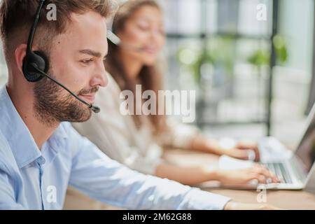 Customer Service Representative With Colleague Working In Office Stock Photo