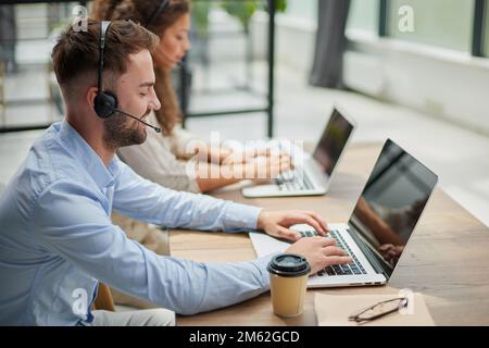 Customer Service Representative With Colleague Working In Office Stock Photo