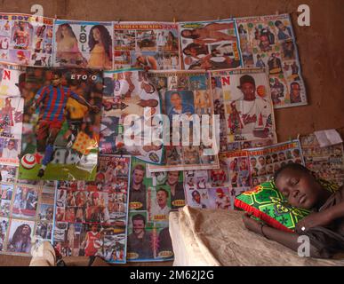 African teenage boy sleeping next to his poster collection in his bedroom room . Stock Photo