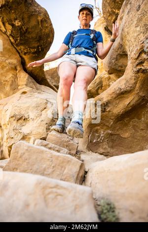 Woman Carefully Walks down Steep Stone Steps on trail in Mesa Verde National Park Stock Photo