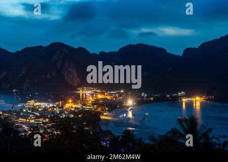 Sunset view over Phi Phi Don from the Viewpoint. Lights glow in the early evening light. Mountains are silhouetted against the sky. Stock Photo