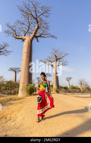 Woman in traditional Malagasy dress posing at Avenue of the Baobabs in Morondava, Madagascar, Africa Stock Photo