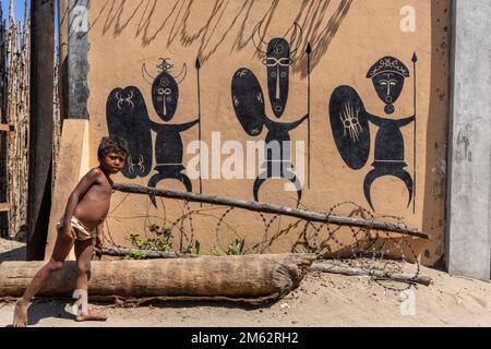 Malagasy boy posing in front of Nosykely village mural, near Morondava, Madagascar, Africa Stock Photo