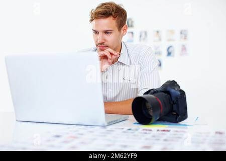 Photographer using laptop. Smart male photographer sitting at table using laptop. Stock Photo