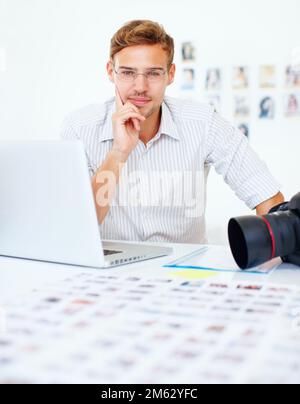 Smart photographer. Portrait of smart photographer using laptop and looking at you. Stock Photo