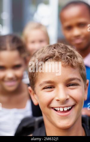 Feeling happy and confident. Closeup of a laughing little boy with friends in the background - copyspace. Stock Photo
