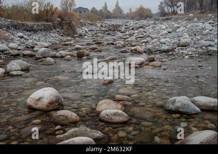 Slow and not deep mountain river with rounded stones Stock Photo