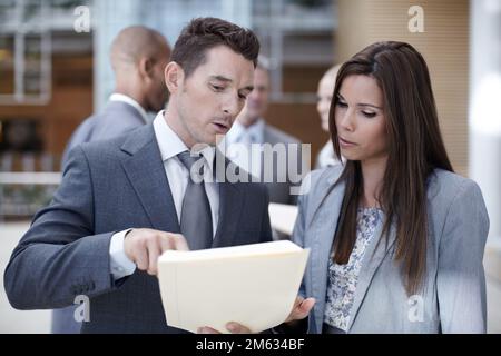 This cant be right. Two coworkers looking over paperwork together while looking serious. Stock Photo