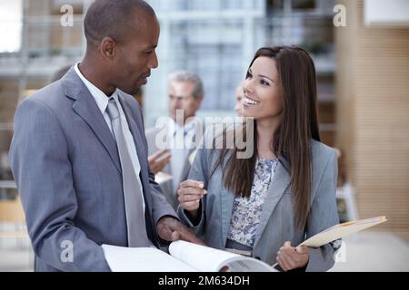 Youve done a thorough job. Two young office associates happily going over some paperwork together. Stock Photo