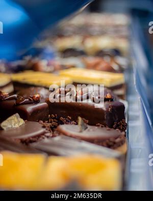 A vertical closeup shot of small cakes with different stuffing on a shelf. Stock Photo
