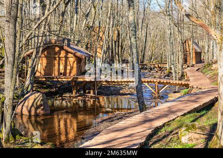 Log cabins by a river with footbridges in a woodland at spring Stock Photo