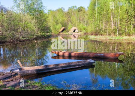 Log boats in a lake with some grass hut on the beach Stock Photo