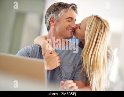 Who needs the internet when we have each other. a happy mature couple using a laptop at home. Stock Photo