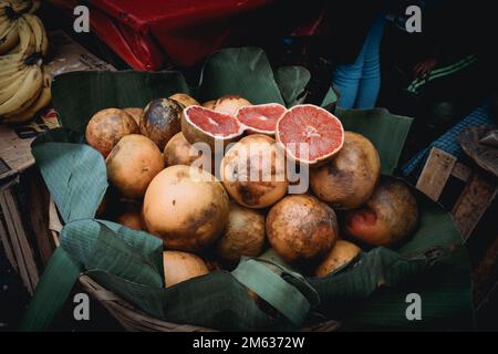 From above of ripe whole and halved grapefruits in wicker basket placed on stall in local street market Stock Photo